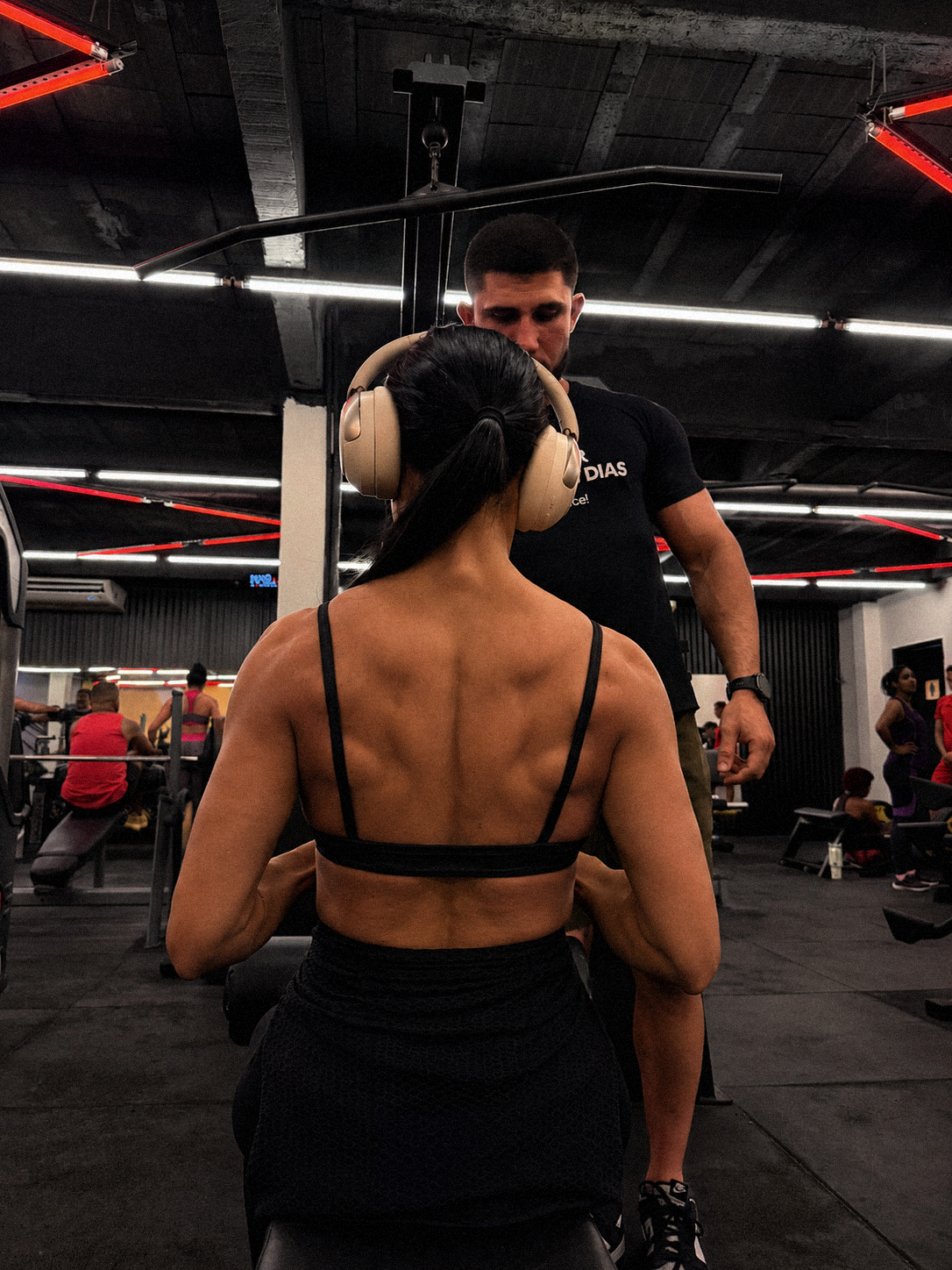 Aluna realizando exercício na polia com acompanhamento do treinador